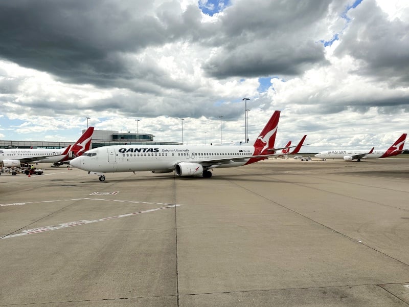 Qantas planes at Brisbane Airport under stormy clouds