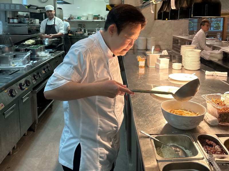 Chef Linda Sim prepares a bowl of laksa in the Qantas Singapore lounge