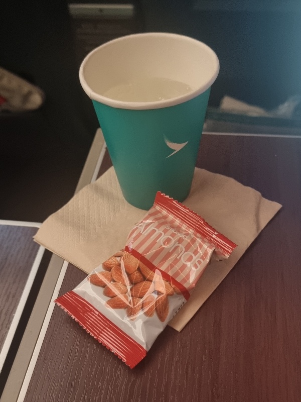 Cathay Pacific Premium Economy drink service with a paper cup