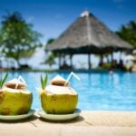 On holiday at a hotel resort swimming pool with two pina colada cocktails