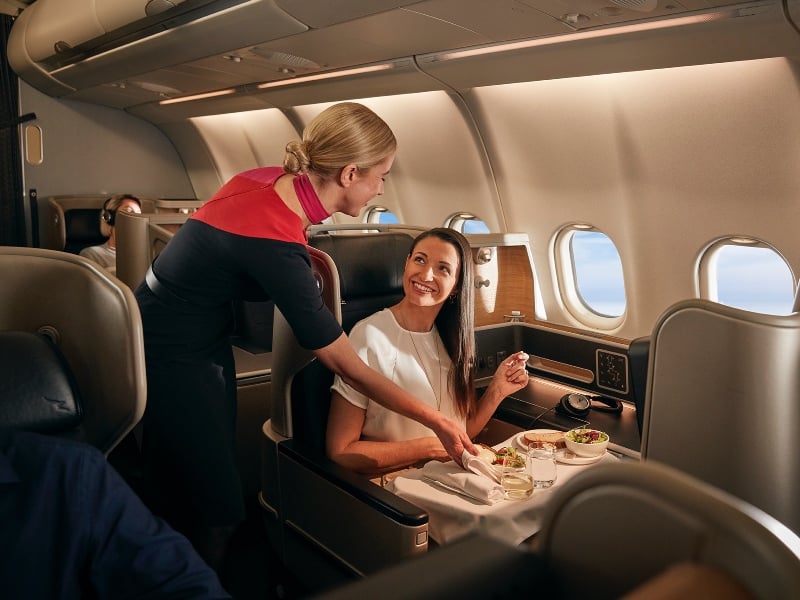 Inflight staff serving food to a female business passenger in the business cabin, Qantas A330