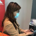 Passenger wearing face mask uses hand sanitiser at Qantas boarding gate